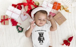 Cute baby mockup of the "Yo Moms Sippy Cup" onesie from BigBabyGorillaBear.Com, with a baby wearing a white onesie and a Christmas Hat, laying on white blanket.