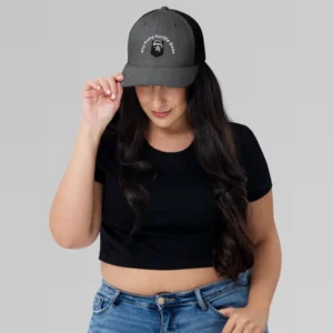 Female model wearing a black, crop top, jeans, and the Charcoal Black Trucker Cap with the Big Baby Gorilla Bear Logo and Brand Name on the front.