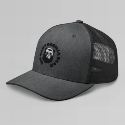 Left side view of a Dark Heather mesh trucker cap, with the Big Baby Gorilla Bear mascot's face and the Big Baby Gorilla Bear Name encircling the face, Embroidered in black and white on the front of the cap.