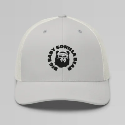 Front side view of a Silver mesh trucker cap, with the Big Baby Gorilla Bear mascot's face and the Big Baby Gorilla Bear Name encircling the face, Embroidered in black and white on the front of the cap.