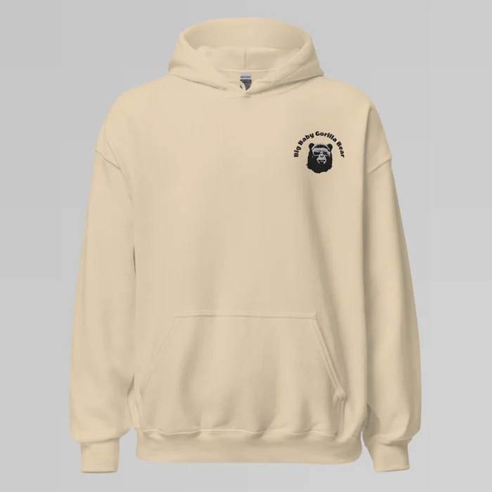 A sand colored hoodie with with the Big Baby Gorilla Bear mascot's face and the Big Baby Gorilla Bear name Embroidered in black and white on the front left breast of the sweater.