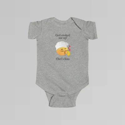 The front of a heather colored baby onesie with the words "God cooked me up!" above a version of the Chef's Kiss emoji. Beneath the emoji, the words "Chef's Kiss" are written.