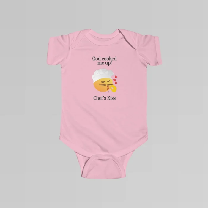 The front of a pink colored baby onesie with the words "God cooked me up!" above a version of the Chef's Kiss emoji. Beneath the emoji, the words "Chef's Kiss" are written.