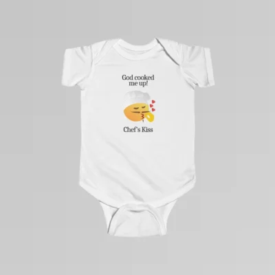 The front of a white colored baby onesie with the words "God cooked me up!" above a version of the Chef's Kiss emoji. Beneath the emoji, the words "Chef's Kiss" are written.