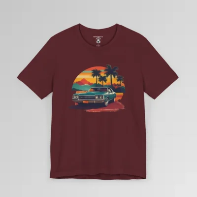 Front of a t-shirt with retro colors of orange, blues, browns, and yellows showing a classic blue-teal car, with palm trees, mountains, and a sky with the sun going down. Maroon colored shirt.