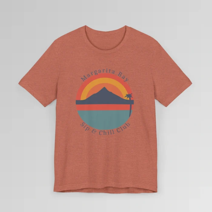 A heather clay colored t-shirt mockup (front) with a circular, minimalistic design of water, sky, mountains, and a palm tree. The colors are orange, yellow, deep blue, and blue. The tee has the words "Margarita Bay" and "Sip & Chill Club" wrapped around the circular design.