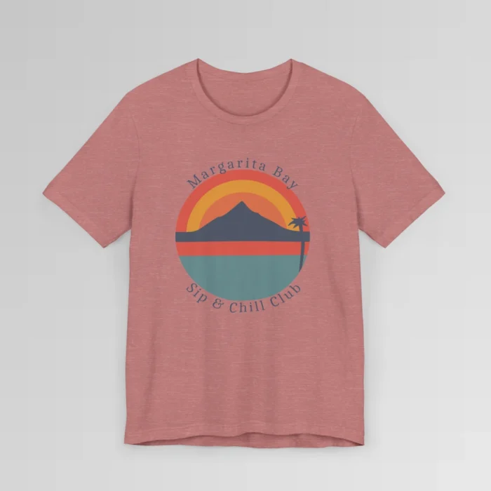 A heather mauve colored t-shirt mockup (front) with a circular, minimalistic design of water, sky, mountains, and a palm tree. The colors are orange, yellow, deep blue, and blue. The tee has the words "Margarita Bay" and "Sip & Chill Club" wrapped around the circular design.