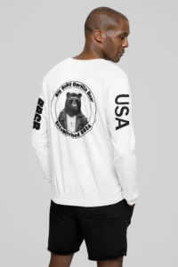 Male model showcasing the backside of the BBGB Classic Full Stack Long Sleeve Tee - White. The backside has the BBGB Logo super-imposed on the upper back portion of the shirt, and the the letters "USA" and BBGB" on the sleeves. The "BBGB" letters has lines going through each letter, adding a trendy blind appearance to the bottom half of the lettering.