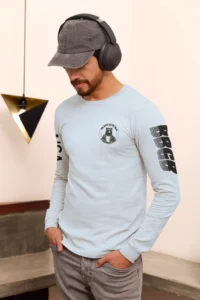 Male model highlighting the front of a light blue long sleeve tee, with the Big Baby Gorilla Bear Logo on the front, and the letters "USA" and "BBGB" opposite sleeves. The "BBGB" letters has lines going through each letter, adding a trendy blind appearance to the bottom half of the lettering.