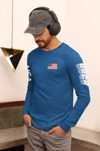 Male Model showing front and left side of the BBGB USA Long Sleeve tee, wearing a hat and headphones, in a room.