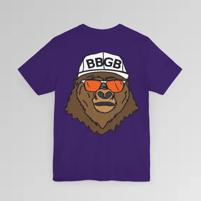 The back of a purple colored shirt, with the Big Baby Gorilla Bear Mascot's face, wearing a white ball cap, and orange and white shades, super imposed on the back of a tee shirt.