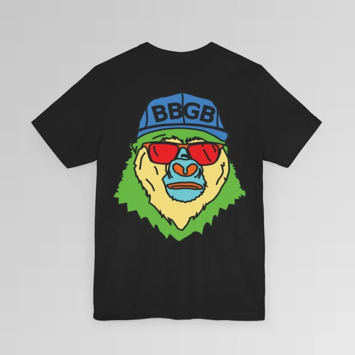 The back of a black colored shirt, with the Big Baby Gorilla Bear Mascot's face in vibrant colors of light blue, green, yellow, and orange, wearing a blue ball cap, and red shades, super imposed on the back of a t-shirt.