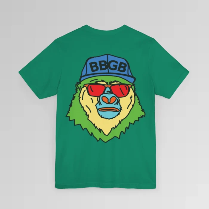 The back of a kelly colored shirt, with the Big Baby Gorilla Bear Mascot's face in vibrant colors of light blue, green, yellow, and orange, wearing a blue ball cap, and red shades, super imposed on the back of a t-shirt.