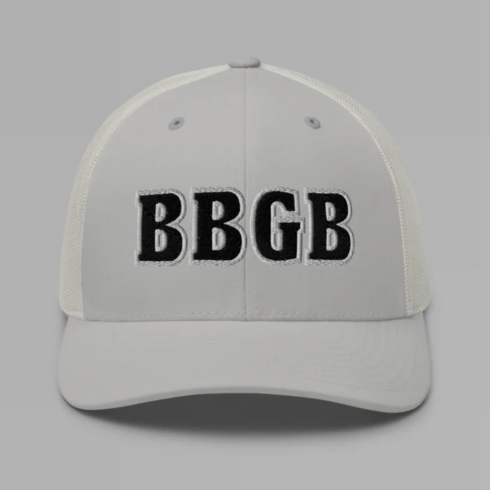 A silver hat with the letters "BBGB" embroidered on the front in black thread, with a white border, on a trucker cap with a mesh back.