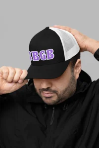 Male model wearing the BBGB Simple Trucker Hat - Purple Edition and a black pull over jacket.