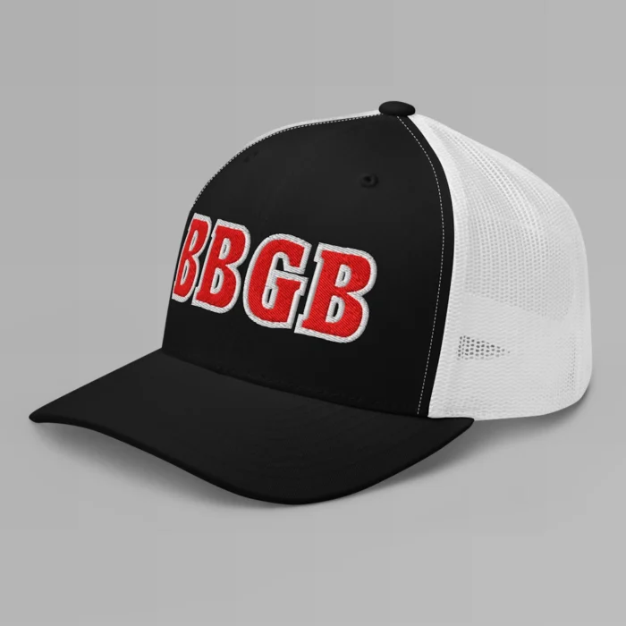 A black and white hat with the letters "BBGB" embroidered on the front in red thread, with a white border, on a trucker cap with a mesh back. (Left Side View)