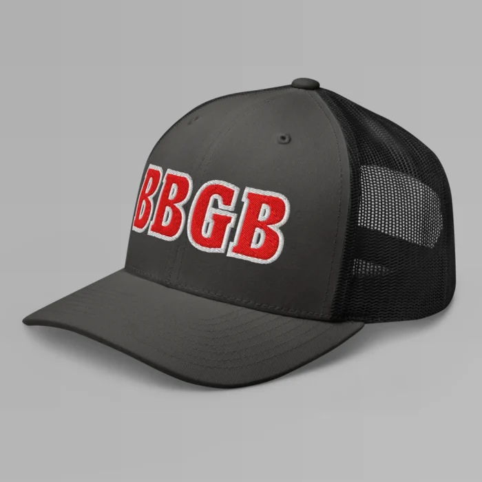 A charcoal and black hat with the letters "BBGB" embroidered on the front in red thread, with a white border, on a trucker cap with a mesh back. (Left Side View)