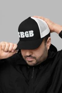 Male model wearing the BBGB Simple Trucker Hat - White Edition and a black pull over jacket.