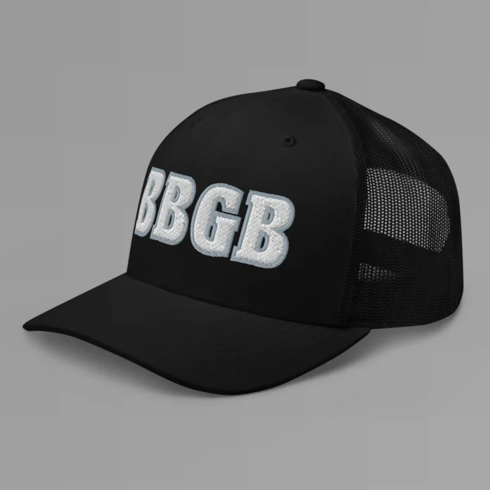 A black hat with the letters "BBGB" embroidered on the front in white thread, with a silver border, on a trucker cap with a mesh back. (Left Side View)