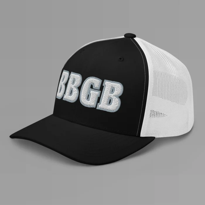 A black and white hat with the letters "BBGB" embroidered on the front in white thread, with a silver border, on a trucker cap with a mesh back. (Left Side View)