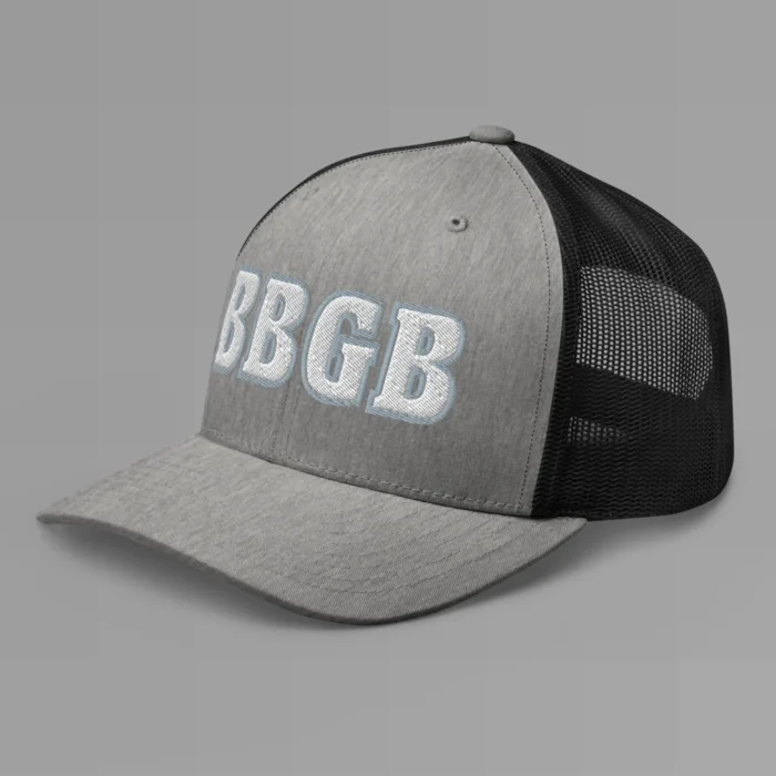 A heather and black hat with the letters "BBGB" embroidered on the front in white thread, with a silver border, on a trucker cap with a mesh back. (Left Side View)