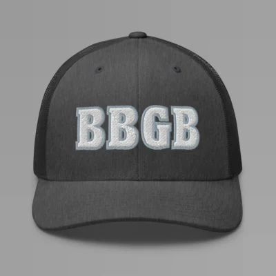 A dark heather grey hat with the letters "BBGB" embroidered on the front in white thread, with a silver border, on a trucker cap with a mesh back.