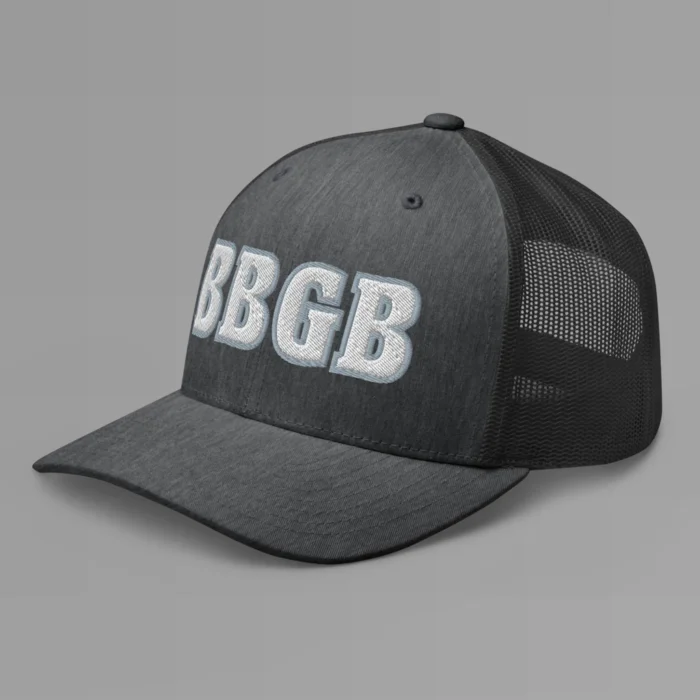 A dark heather grey hat with the letters "BBGB" embroidered on the front in white thread, with a silver border, on a trucker cap with a mesh back. (Left Side View)