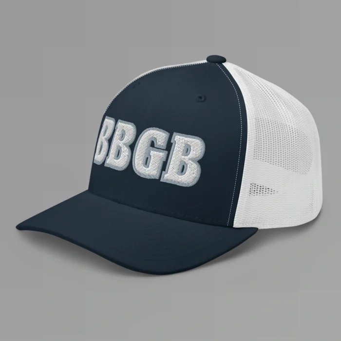 A navy and white hat with the letters "BBGB" embroidered on the front in white thread, with a silver border, on a trucker cap with a mesh back. (Left Side View)