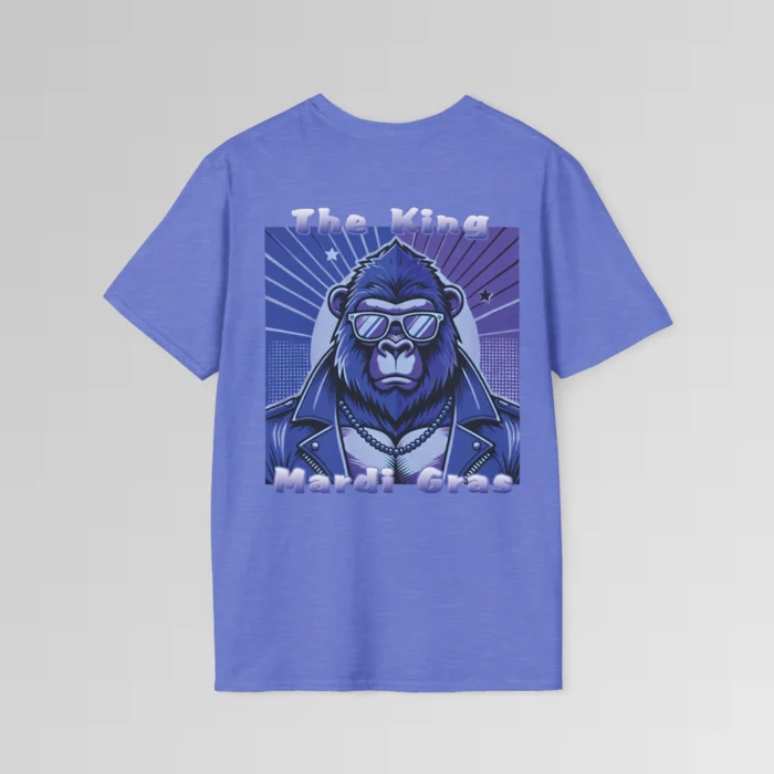 The backside of a heather royal colored tee with a swag looking gorilla bear wearing shades, with a sun like object with rays shooting out from behind the character. The words "The King" are above the graphic, and "Mardi Gras" beneath the graphic. The entire image is in varying shades of purple.