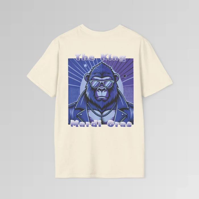 The backside of a natural colored tee with a swag looking gorilla bear wearing shades, with a sun like object with rays shooting out from behind the character. The words "The King" are above the graphic, and "Mardi Gras" beneath the graphic. The entire image is in varying shades of purple.