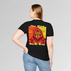 Female model in black t-shirt showing the back of a tee with a red and orange graphic of a swag looking gorilla bear character, wearing shades, with a sun behind it, in a retro style, and the words "The King" and "Mardi Gras" in a gradient colored yellow to green font.