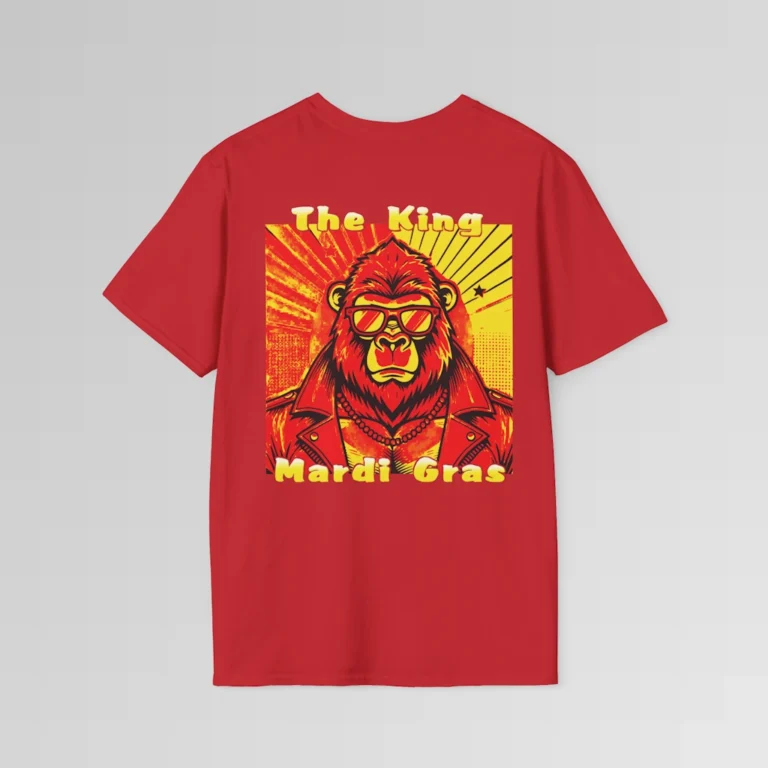 The backside of a red colored tee with a swag looking gorilla bear wearing shades, with a sun like object with rays shooting out from behind the character. The words "The King" are above the graphic, and "Mardi Gras" beneath the graphic. The entire image is in varying shades of red, yellow, and orange.