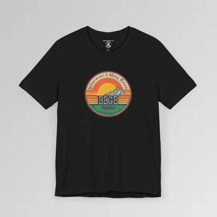 The front of a black tee. with a circular, retro sunset design, with mountains, the letters "BBGB", "2025" in the middle, and the words "Wherever I May Roam" on the top of the circle. Red, Deep blue, teal, orange, yellow, and cream colors in the design.