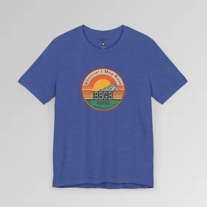 The front of a heather royal tee. with a circular, retro sunset design, with mountains, the letters "BBGB", "2025" in the middle, and the words "Wherever I May Roam" on the top of the circle. Red, Deep blue, teal, orange, yellow, and cream colors in the design.