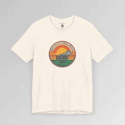 The front of a natural tee. with a circular, retro sunset design, with mountains, the letters "BBGB", "2025" in the middle, and the words "Wherever I May Roam" on the top of the circle. Red, Deep blue, teal, orange, yellow, and cream colors in the design.