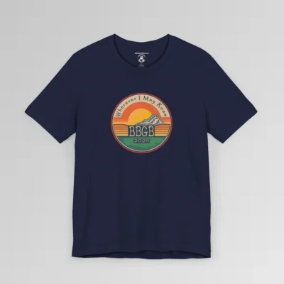 The front of a navy tee. with a circular, retro sunset design, with mountains, the letters "BBGB", "2025" in the middle, and the words "Wherever I May Roam" on the top of the circle. Red, Deep blue, teal, orange, yellow, and cream colors in the design.