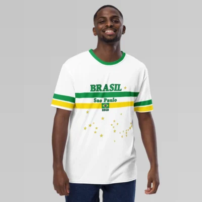 A male model showcasing the frontside of the Sao Paulo Brasil Luxurious Tee from BigBabyGorillaBear.Com. This shirt has a green collar, green and yellow sleeve stripes, and green and yellow bands on the front. The words "Brasil" and "Sao Paulo" are above and below the green band. The Brazilian Flag is in the center of the yellow band. "BBGB" is beneath the flag. Stars are scattered on the shirt in the pattern similar to the Brazilian flag.