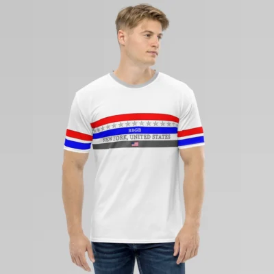 Male model looking left, wearing the New York United States Luxurious Tee from BigBabyGorillaBear.Com, on a hanger. The shirt has three bands across the chest (red, blue, and dark grey). Light grey stars span across and in between the red and blue bands. a white "BBGB" is centered inside the blue band. Light grey "New York, United States" is centered between the blue and dark grey bands. in the center of the dark grey band is a small American flag, centered. The sleeves have red and blue stripes, with a black outline.