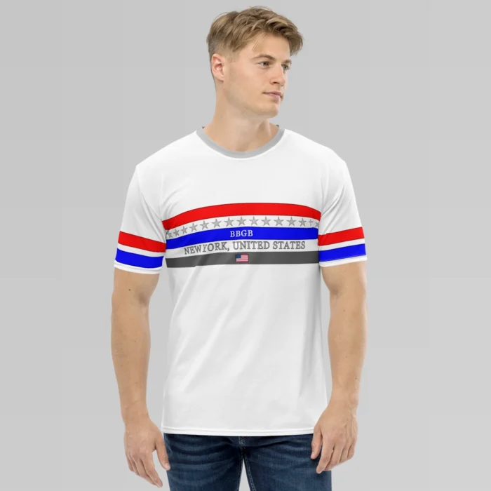 Male model looking left, wearing the New York United States Luxurious Tee from BigBabyGorillaBear.Com, on a hanger. The shirt has three bands across the chest (red, blue, and dark grey). Light grey stars span across and in between the red and blue bands. a white "BBGB" is centered inside the blue band. Light grey "New York, United States" is centered between the blue and dark grey bands. in the center of the dark grey band is a small American flag, centered. The sleeves have red and blue stripes, with a black outline.